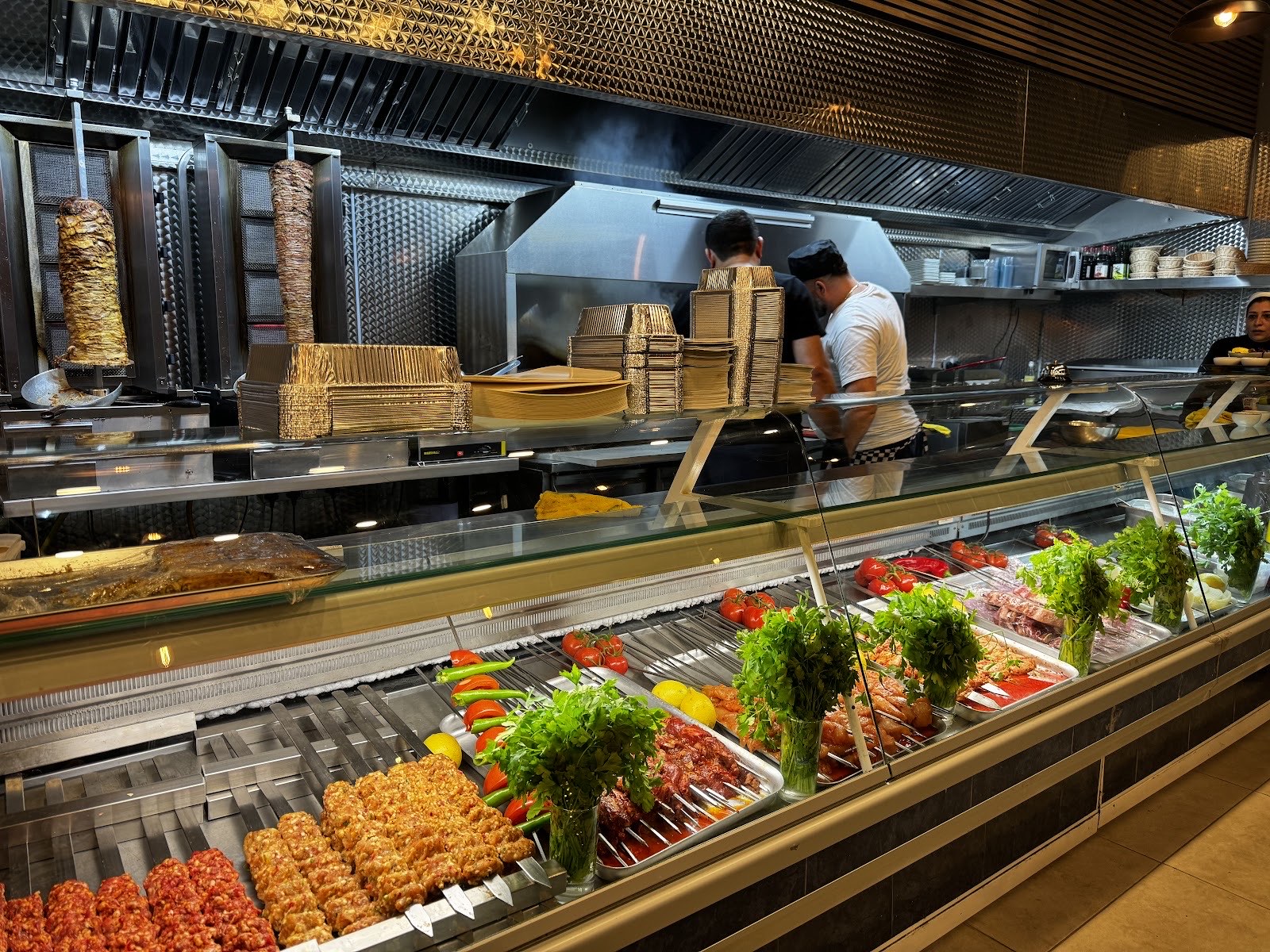 Kohinoor's open charcoal grill counter with doner spits and skewers of adana and shish being prepared