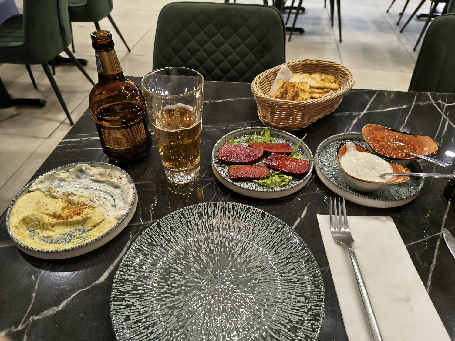 A meze spread at Kohinoor: hummus, cacik, sucuk and warm bread on a marble table