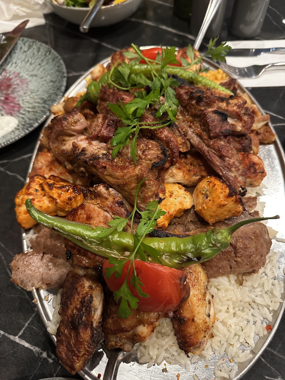 Kohinoor's mixed charcoal grill platter: lamb chops, chicken shish, adana kofte, lamb doner and wings piled on rice with grilled chilli and tomato