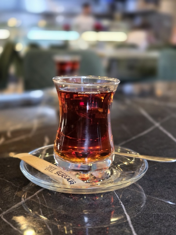 A glass of Turkish tea in a traditional tulip glass on the marble table